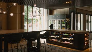 A modern bar area with a counter, stools, and a refrigerated display case.