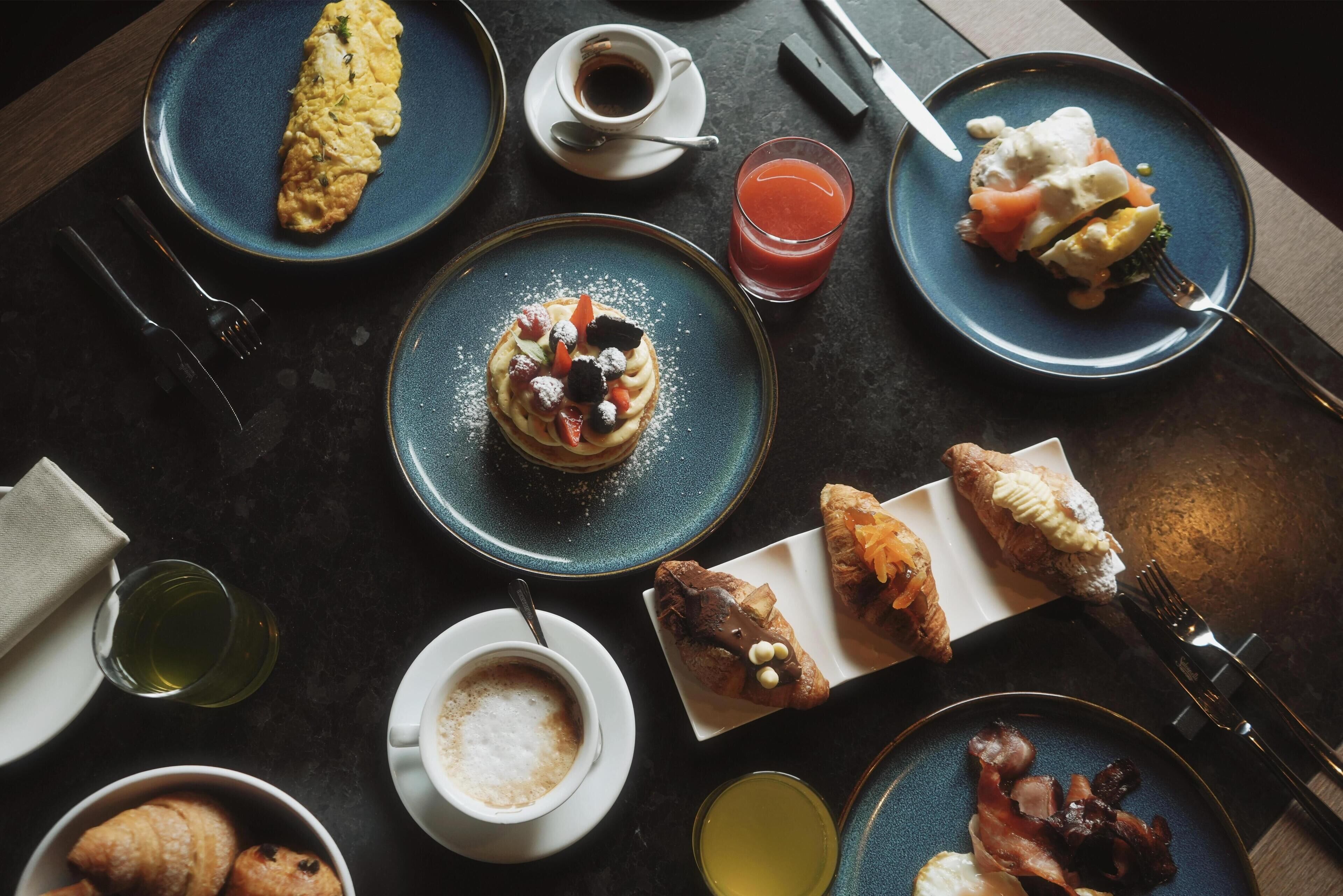 A breakfast setting with various dishes including an omelette, pastries, and a glass of juice.