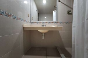 Un baño con lavamanos, espejo y paredes de azulejos.
