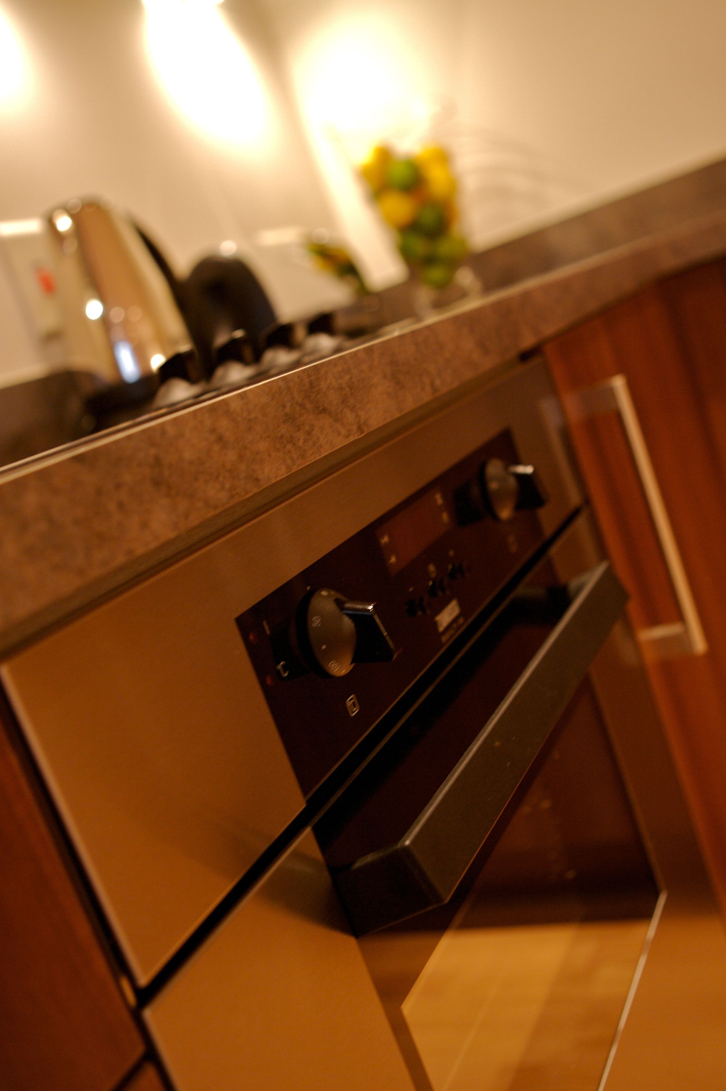 Una cucina con cappa in acciaio inossidabile, forno integrato e un piano di lavoro con una macchina da caffè.