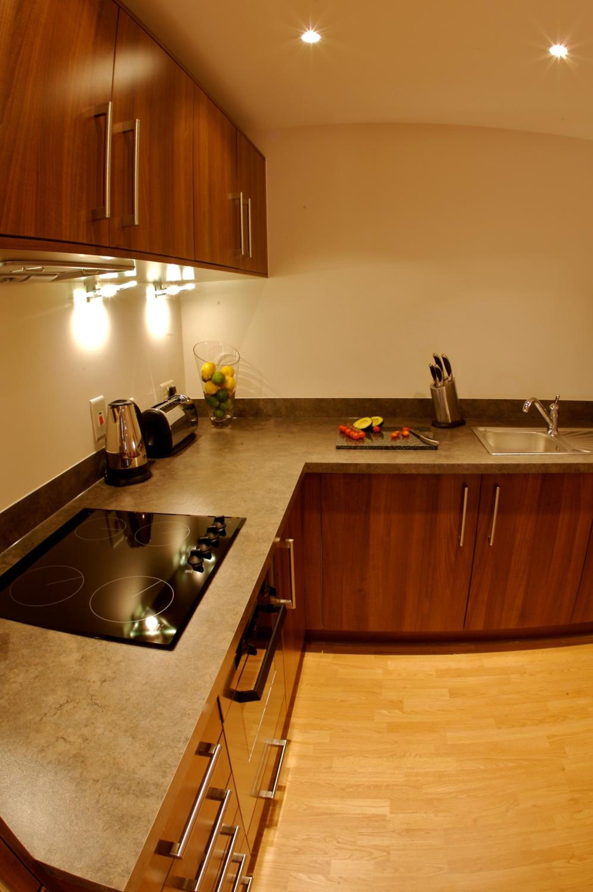 Una cocina moderna con armarios de madera, un lavamanos de acero inoxidable y una estufa empotrada.