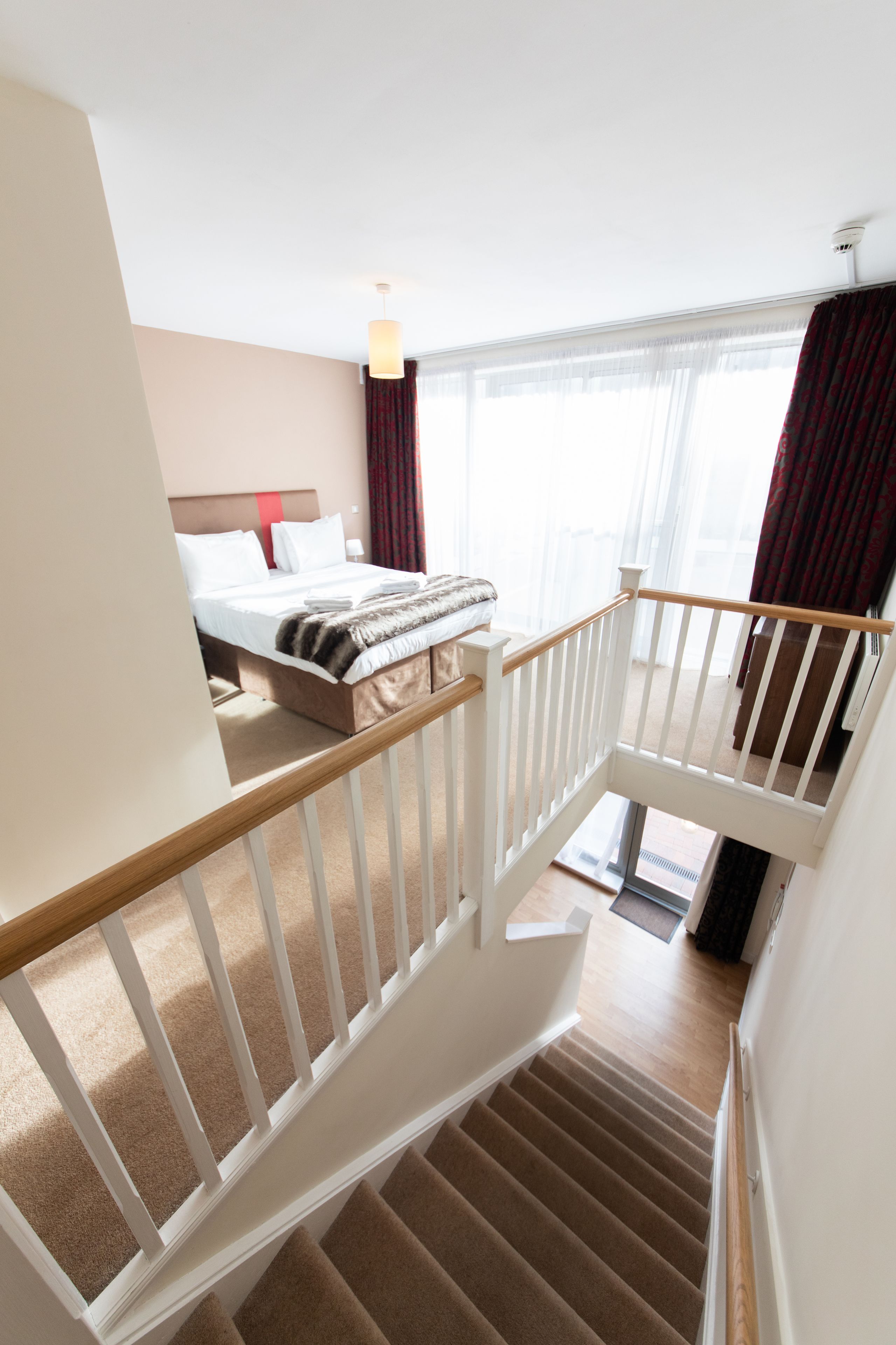 A hotel room with a bed, a staircase, and a view of the outdoors.