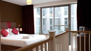 A hotel room with a large bed, a TV, and a balcony with a city view. - The Spires Serviced Apartments Birmingham (Birmingham)