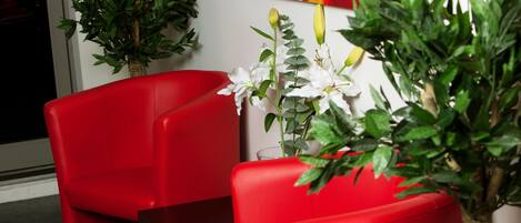 A room with two red chairs, a small table, and a potted plant.