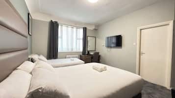 A hotel room with two beds, a flat-screen TV, a desk, and a window with curtains.