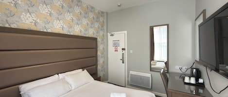 A hotel room with a bed, a dresser, a mirror, a radiator, and a television.