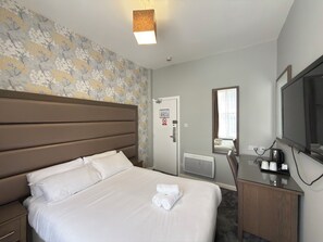 A hotel room with a bed, a dresser, a mirror, a radiator, and a television. - Lord Nelson Hotel – Lime Street Station Liverpool by Compass Hospitality (Liverpool)