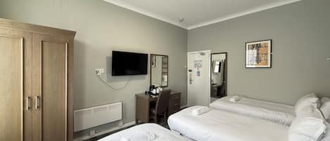 Een hotelkamer met twee bedden, een televisie, een kledingkast en een bureau met stoel.