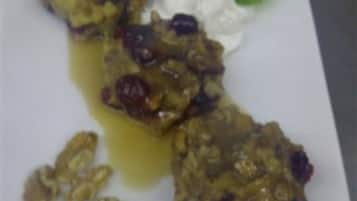 Une assiette contenant un dessert composé d’une compote de fruits, d’une cuillerée de crème et d’une feuille verte en guise de décoration.