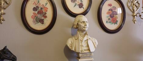 Busto de Jefferson con tres cuadros enmarcados de flores en la pared de fondo.