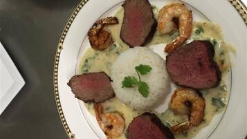 Un plato de comida con bisteck, camarones y arroz.