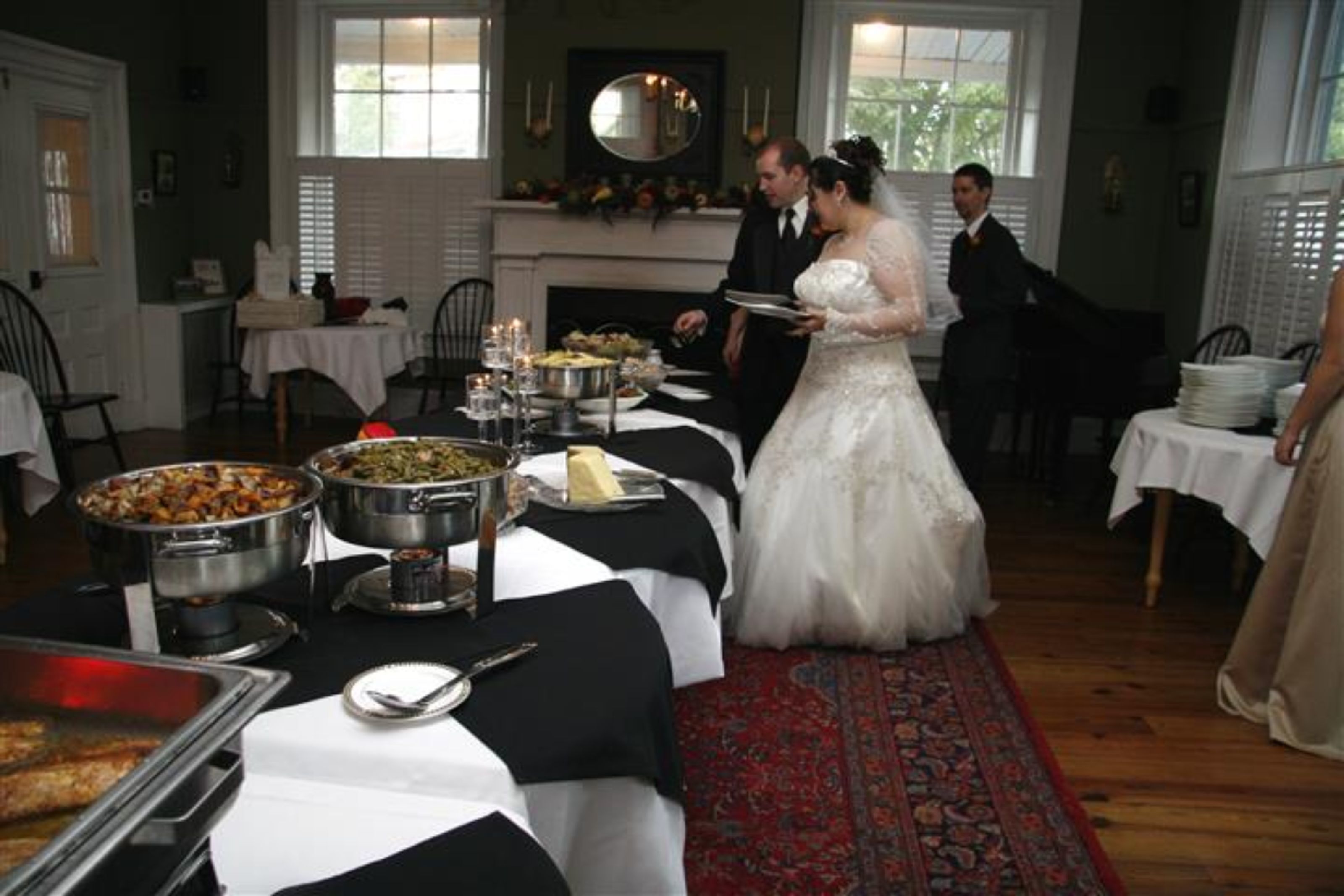 Une réception de mariage avec un buffet, des invités, ainsi qu’une mariée et un marié.