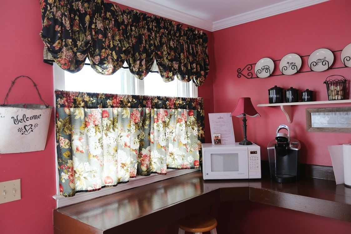 A kitchen with a microwave, coffee maker, and a 'Welcome' sign on the wall.