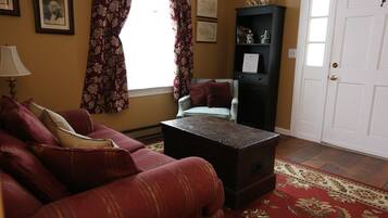 A living room with a red sofa, a small table, a bookshelf, and a door.