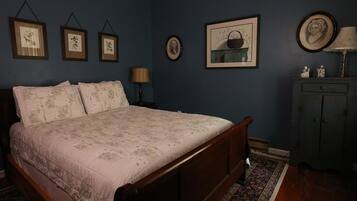 A bedroom with a wooden bed, a nightstand, a dresser, and a patterned rug.