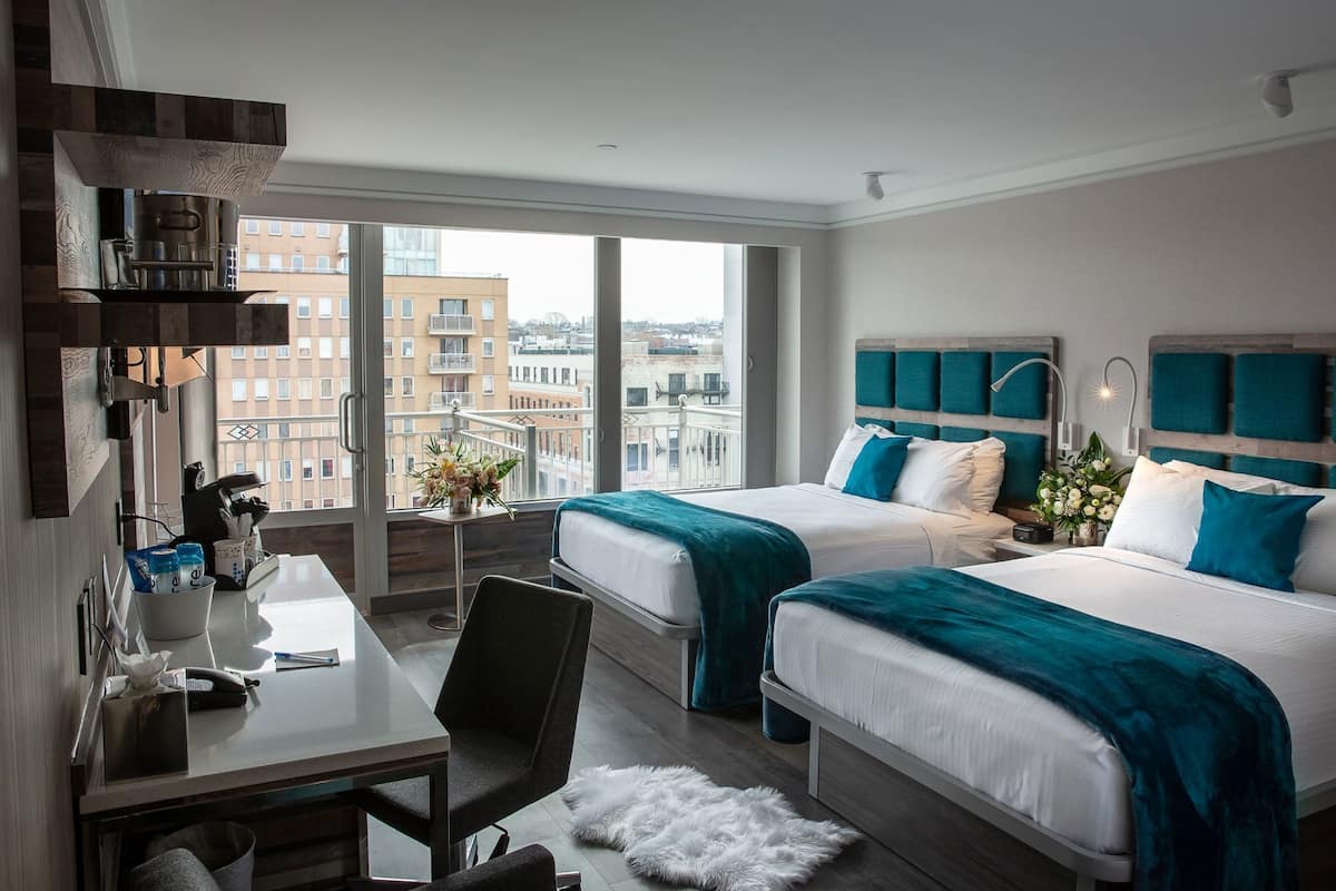 Habitación de hotel con dos camas, un escritorio y una silla.