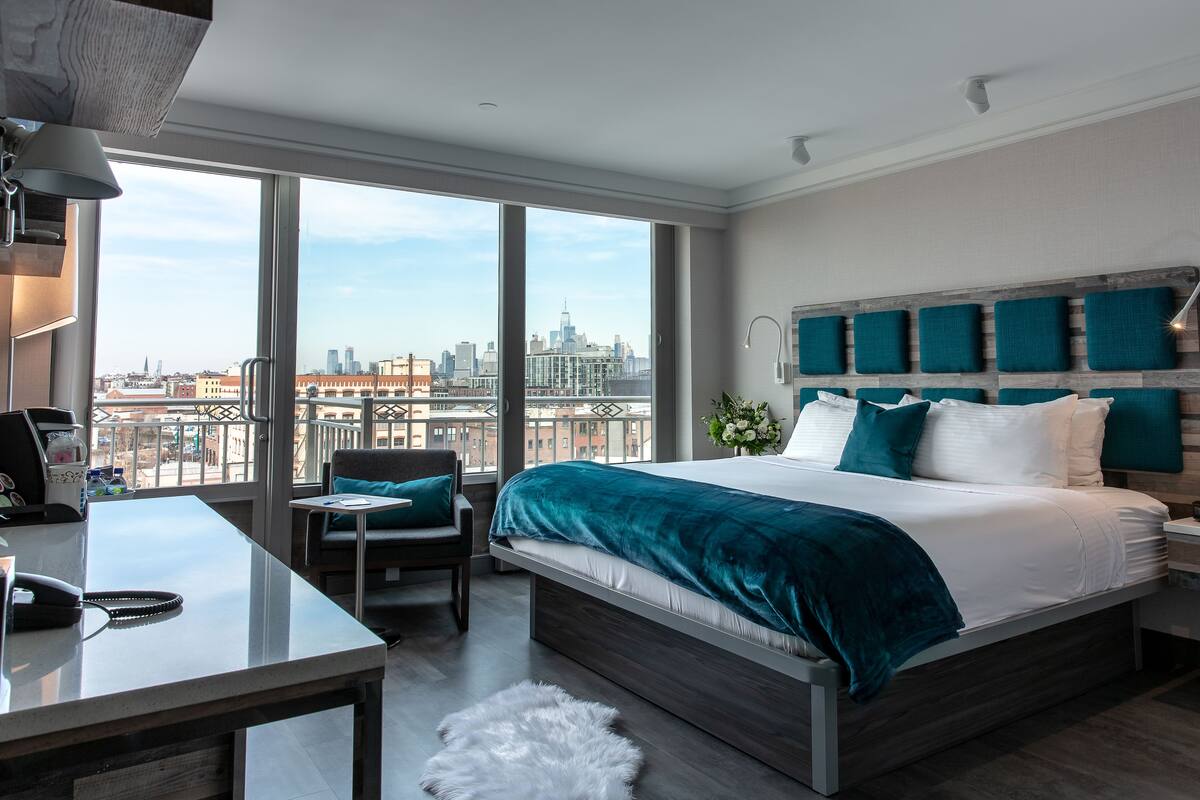 Habitación de hotel moderna con una cama grande, un escritorio y vistas a la silueta urbana.