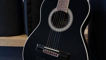 A black guitar with a circular sound hole and a logo on the body.