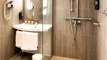 A modern bathroom with a glass shower enclosure, a sink with a towel, and a hairdryer.
