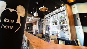Una zona de bar con mostrador, lámparas colgantes y estanterías llenas de botellas.