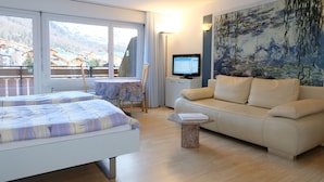 A hotel room with a bed, a sofa, a TV, and a painting. - Artist Apartments & Hotel Garni (Zermatt)