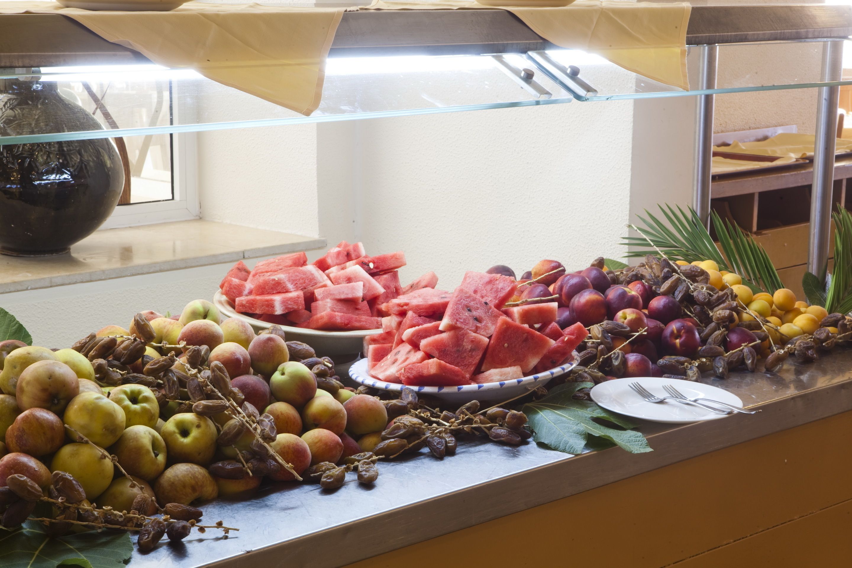 A buffet with various fruits and vegetables, including apples, watermelon, and peaches.