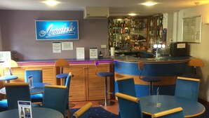 A bar area with blue chairs and tables, a sign reading "Anabels", and a bar stocked with various bottles.