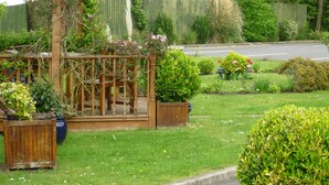 A garden with a wooden pergola, various potted plants, and a well-maintained lawn.