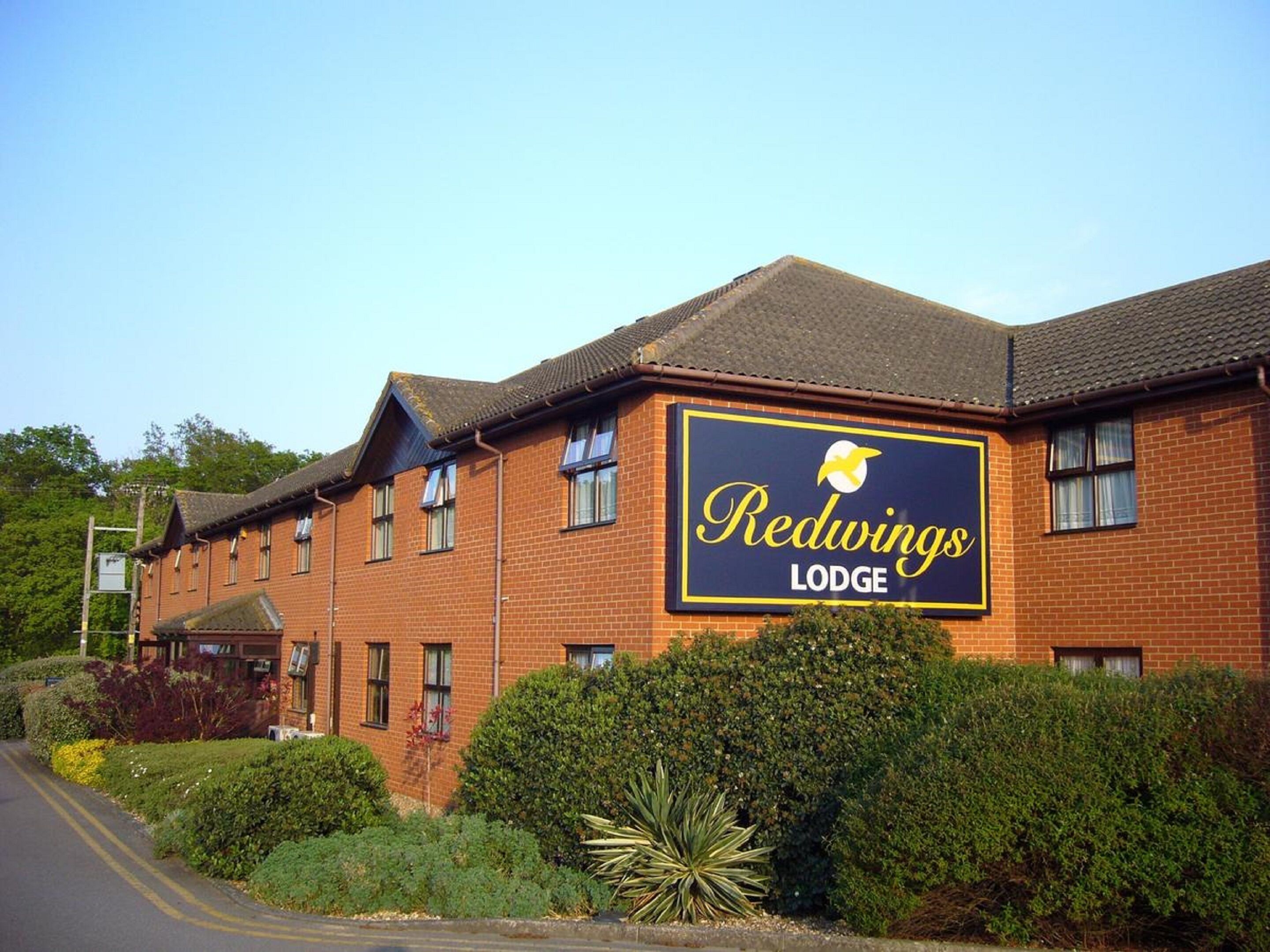 A Redwings Lodge building with a prominent sign, brick facade, and surrounding greenery.