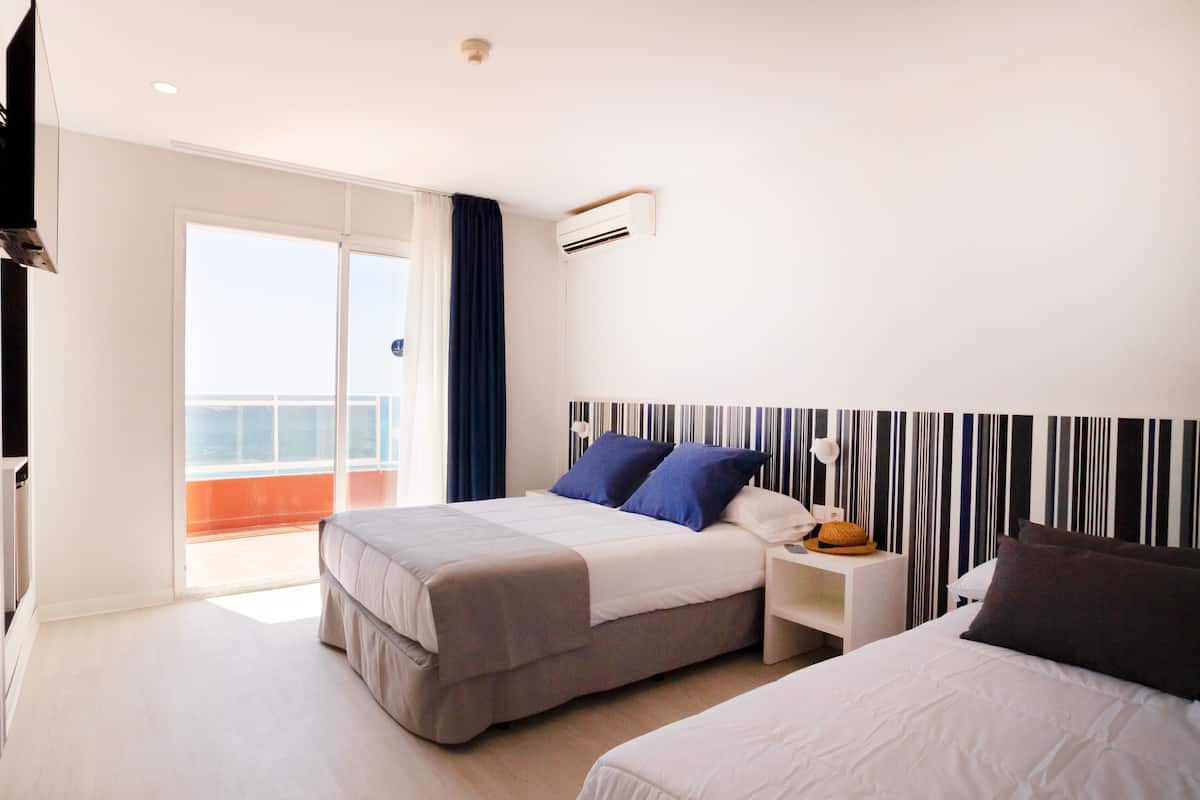 A hotel room with a bed, bedside table, and a view of the balcony.