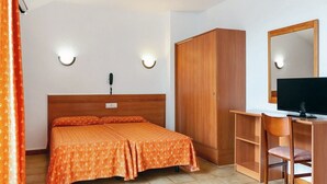 A bedroom with a double bed, a wooden wardrobe, a desk with a chair, and a television. - Santa Susanna Resort Affiliated by FERGUS (Santa Susanna)