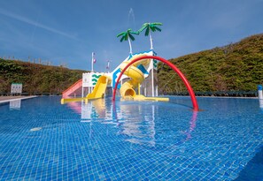 Une piscine dotée d’un espace de jeux aquatiques comprenant des toboggans et un grand toboggan aquatique.