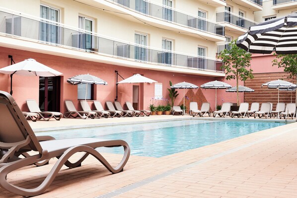 Alberca al aire libre, sombrillas en la alberca y camastros 