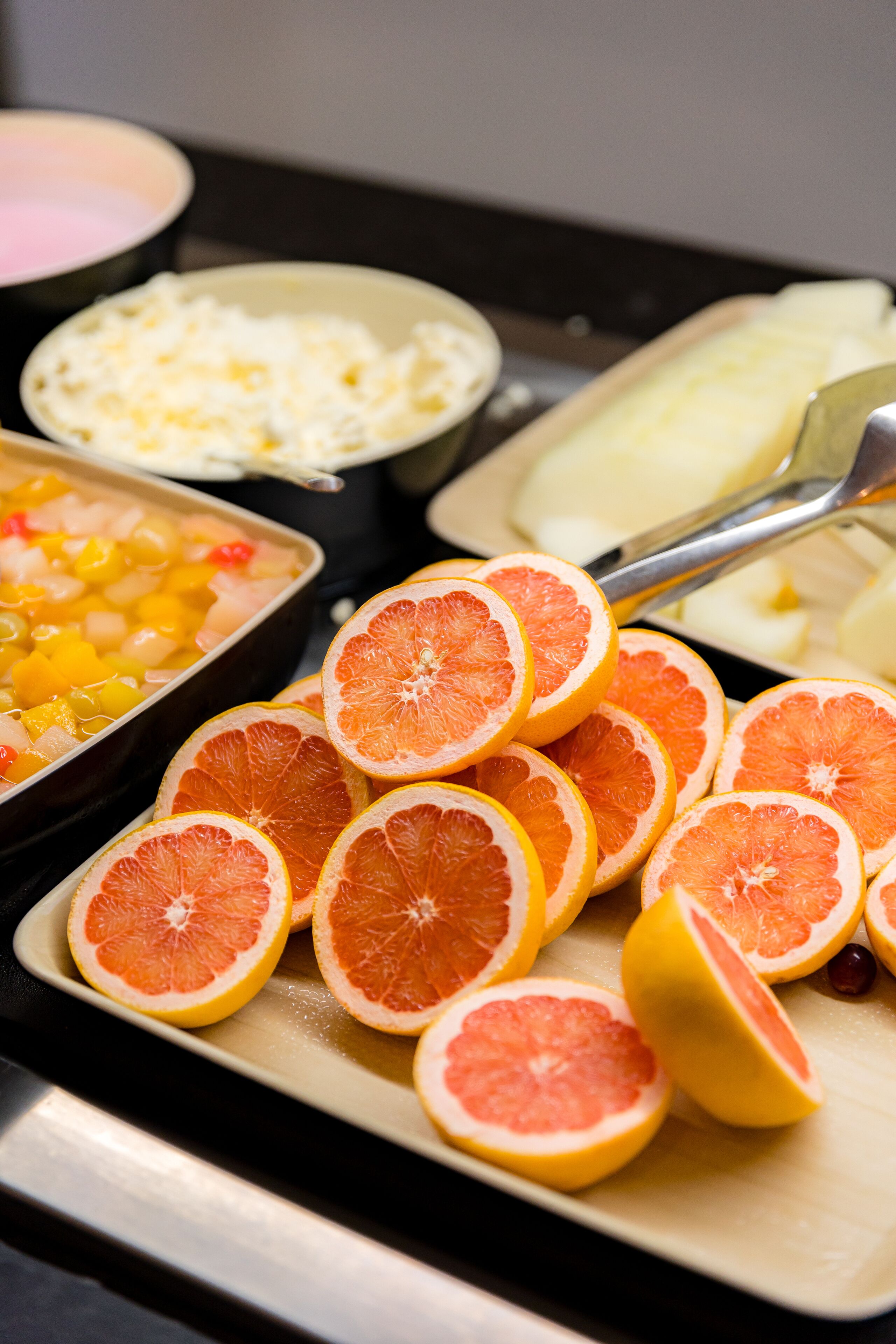 A buffet with various food items including sliced oranges and a dish with diced fruit.