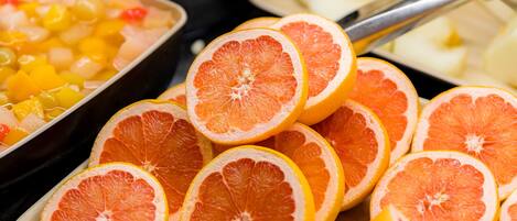 A buffet with various food items including sliced oranges and a dish with diced fruit.