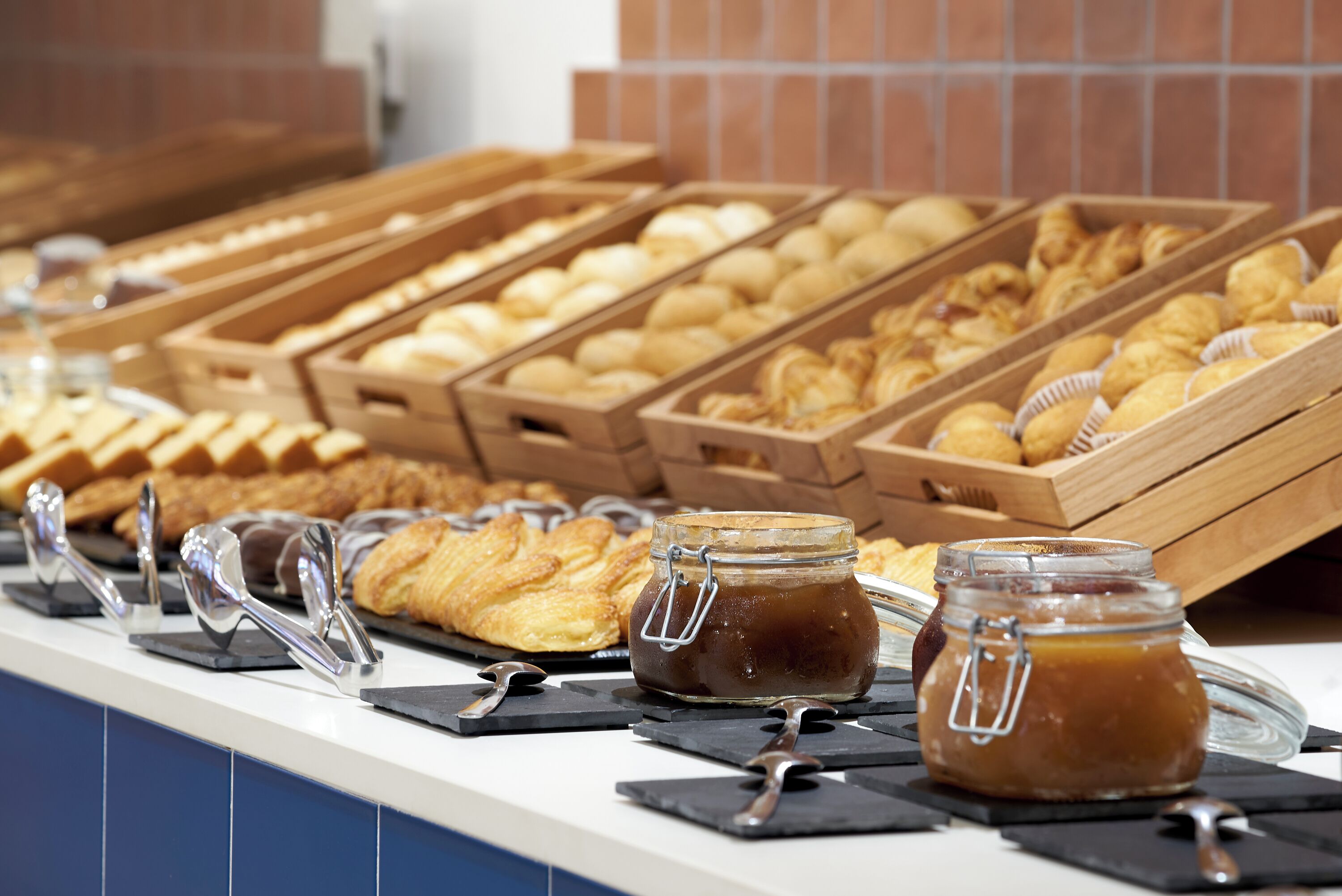 A buffet with various baked goods and jars of jam.