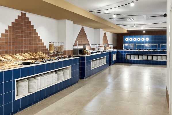 Zona de bufé con mostradores de azulejos azules, un letrero que dice 'BRUNCH' y alimentos dispuestos con cuidado.