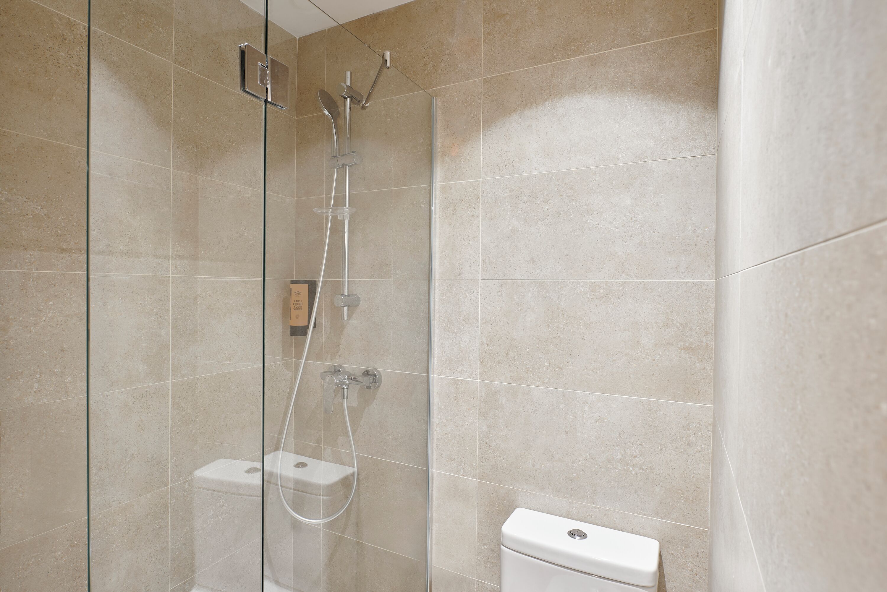 A bathroom with a glass-enclosed shower, a toilet, and a wall-mounted towel rack.