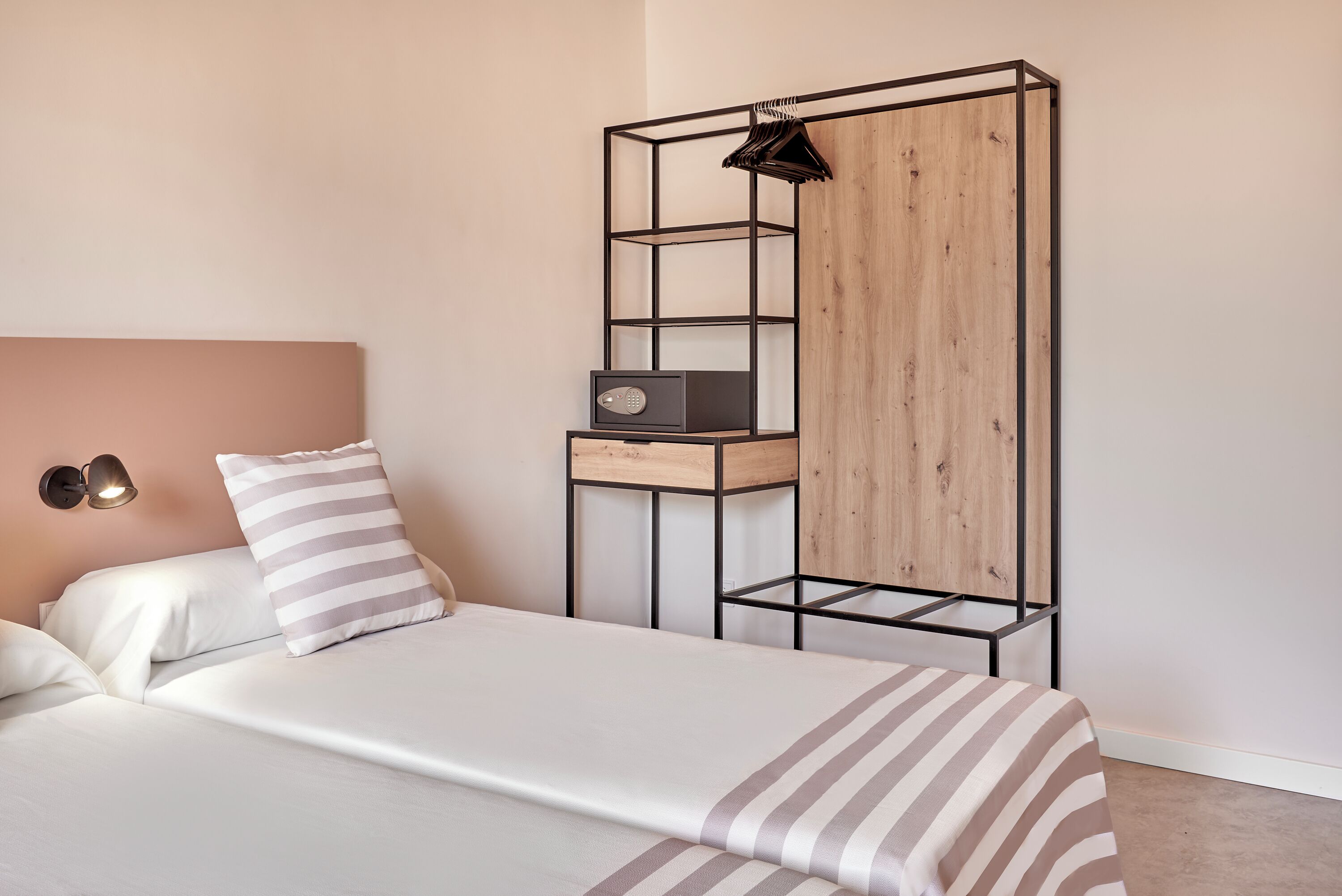 Une chambre à coucher comprenant un lit, une armoire en bois, une étagère et une lampe fixée au mur.