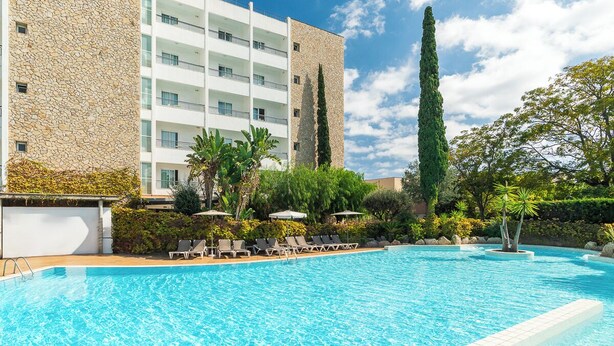 A swimming pool with lounge chairs, a stone building, and a clear sky.