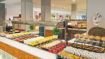 Un buffet proposant une variété de plats et de boissons, notamment des pâtisseries, des fruits et des desserts.