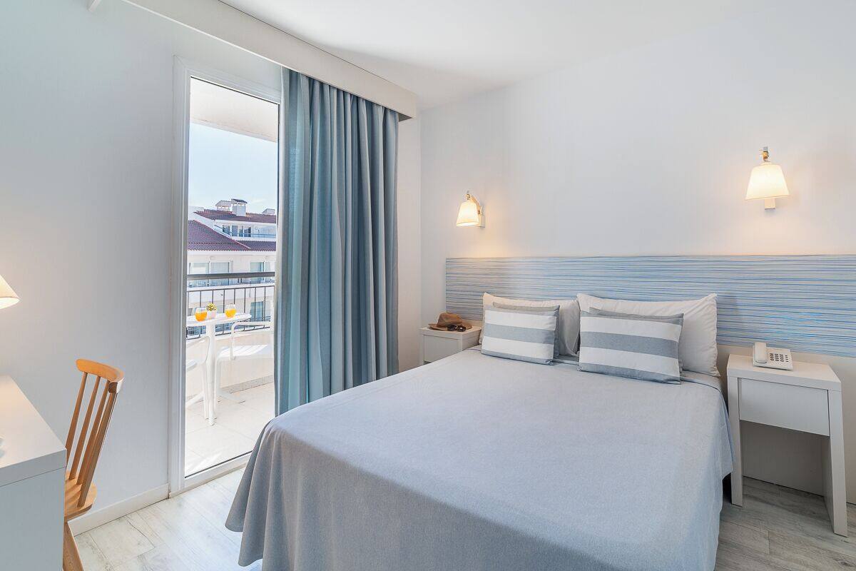 Hotelkamer met een bed, nachtkastje, stoel, bureau en uitzicht op het buitenbalkon.