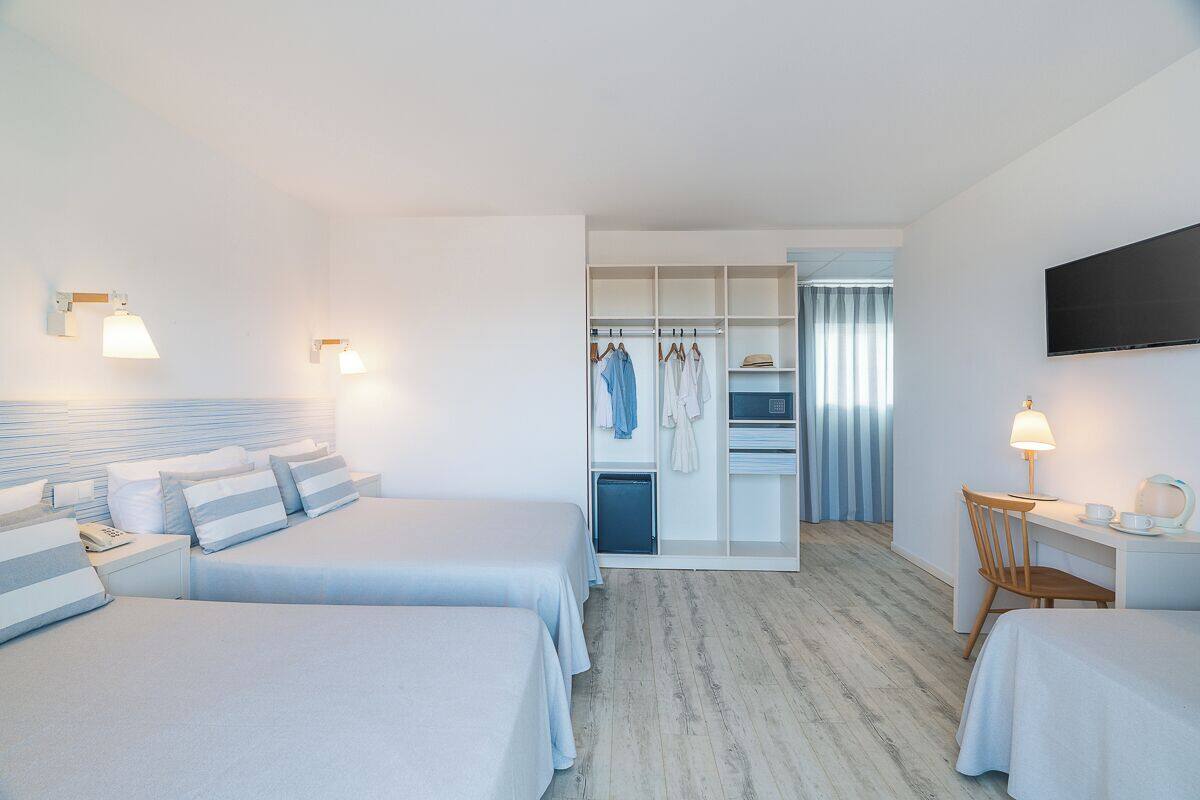 Een hotelkamer met twee bedden, een bureau met stoel, een kledingkast en een aan de muur bevestigde televisie.