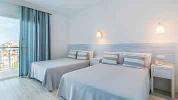 Habitación de hotel con dos camas, un balcón con vistas y un paisaje urbano a la vista a través de la ventana.