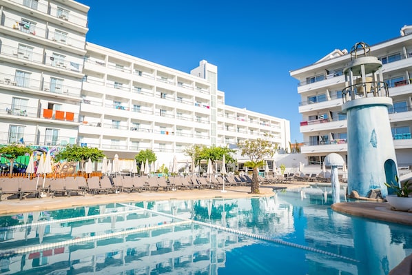 Een buitenzwembad, ligstoelen bij het zwembad