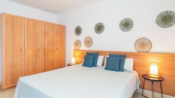 Une chambre à coucher avec un grand lit, une armoire en bois et des œuvres d’art décoratives au mur.