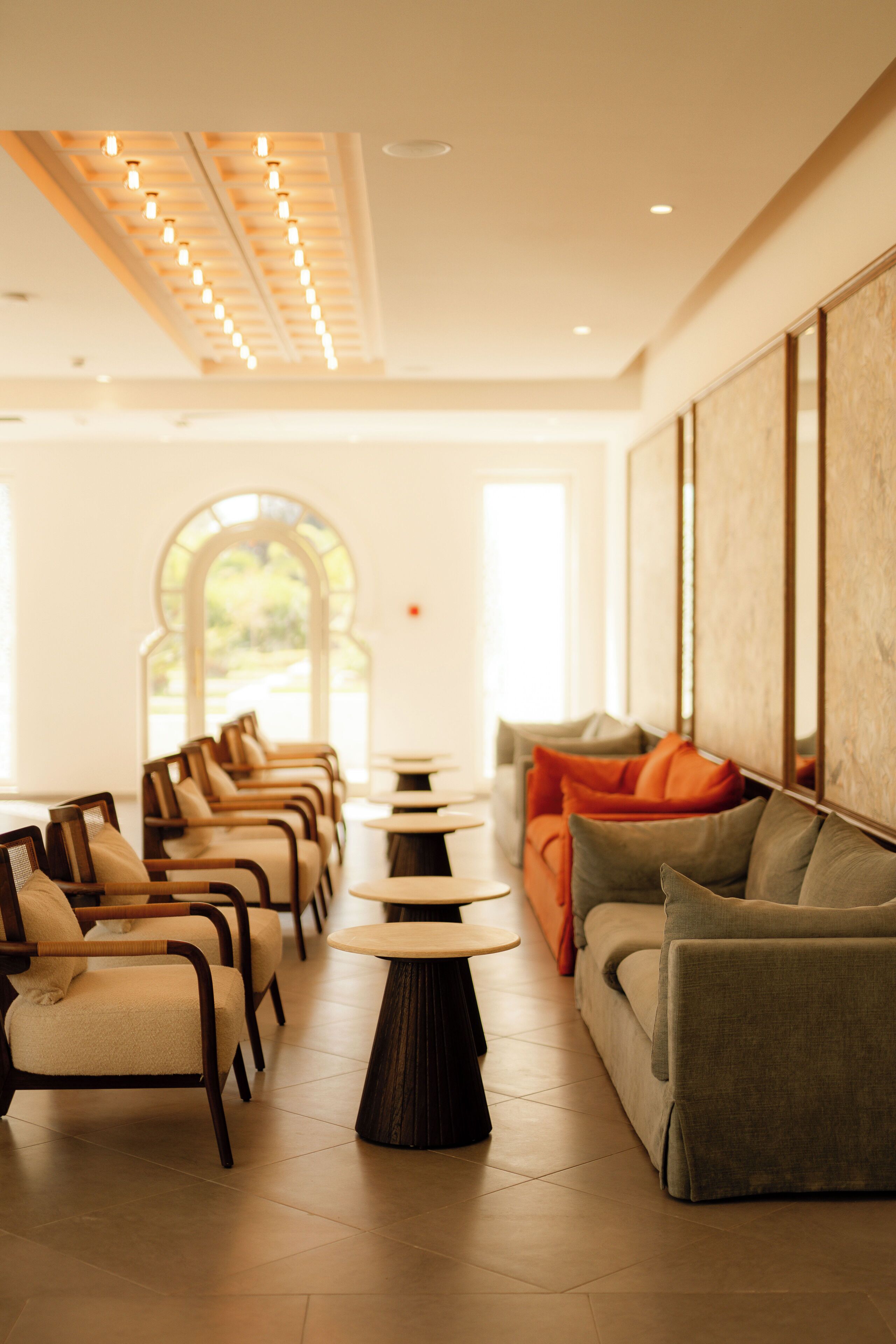 A modern interior with a row of chairs, a sofa, and a central table, suggesting a waiting area or lounge.