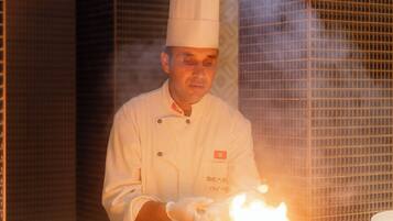 A chef in a professional kitchen with a stove in the foreground.