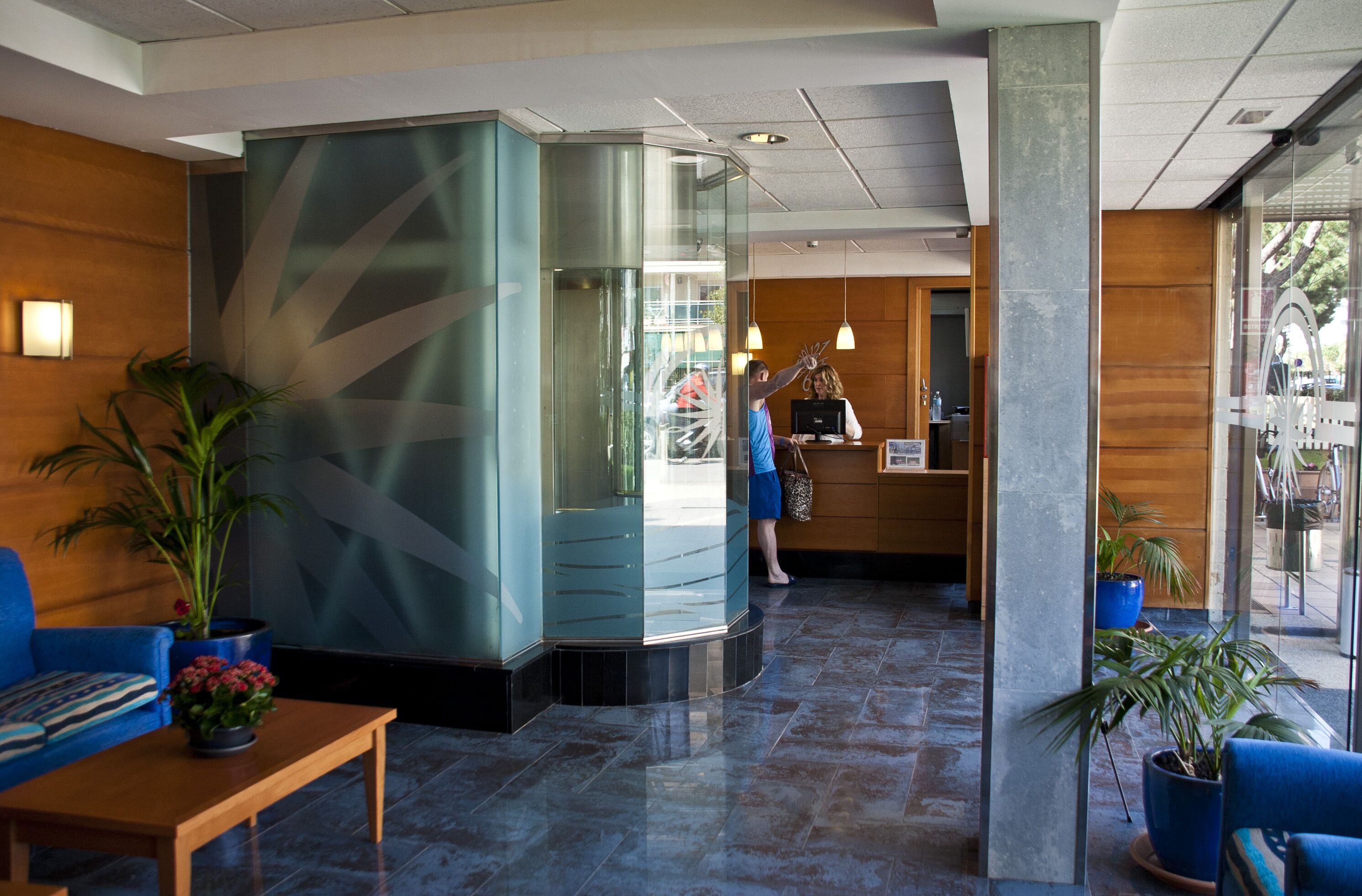 A lobby with a reception desk, a blue sofa, and potted plants.