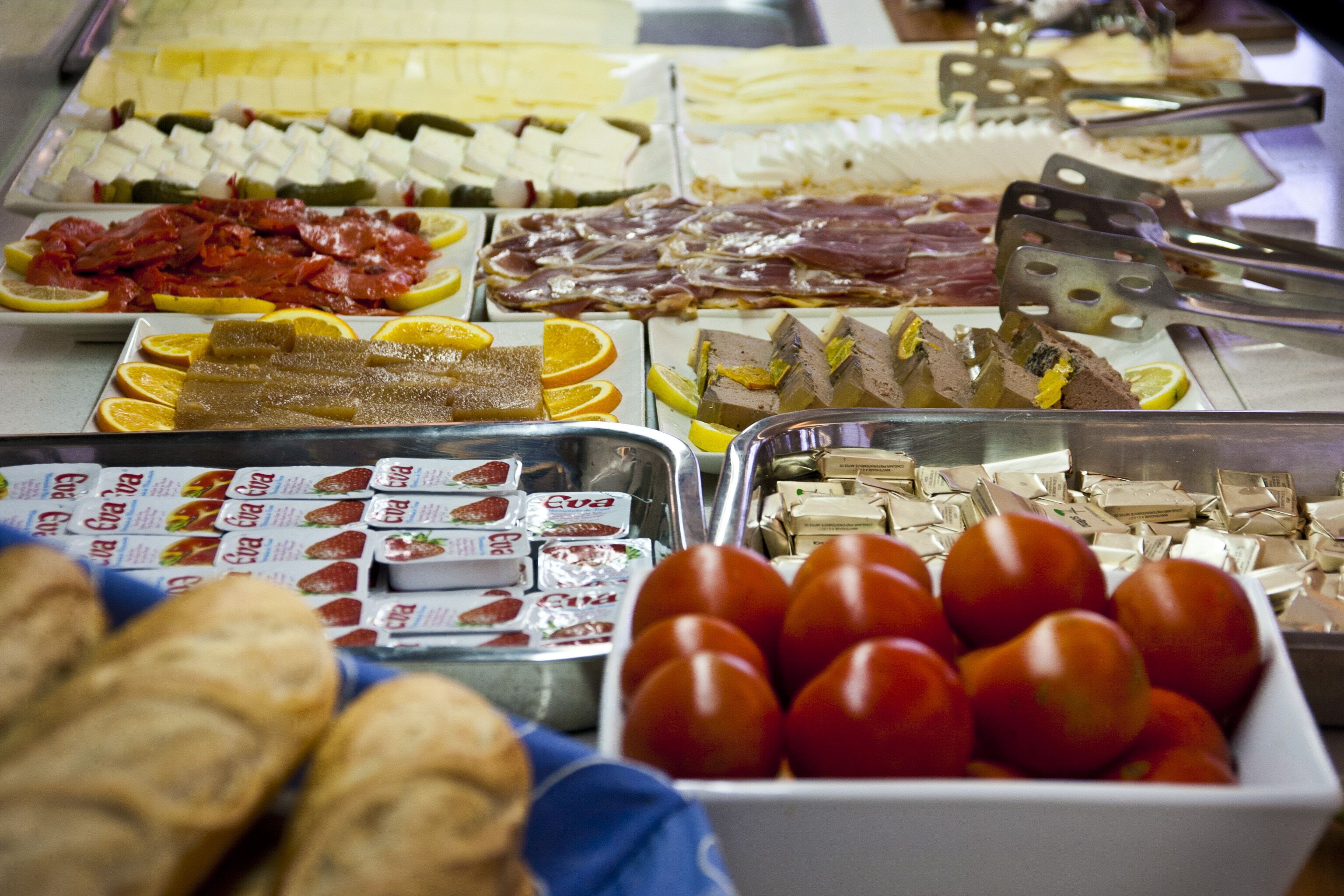 A buffet with various food items including meats, cheeses, and fruits.